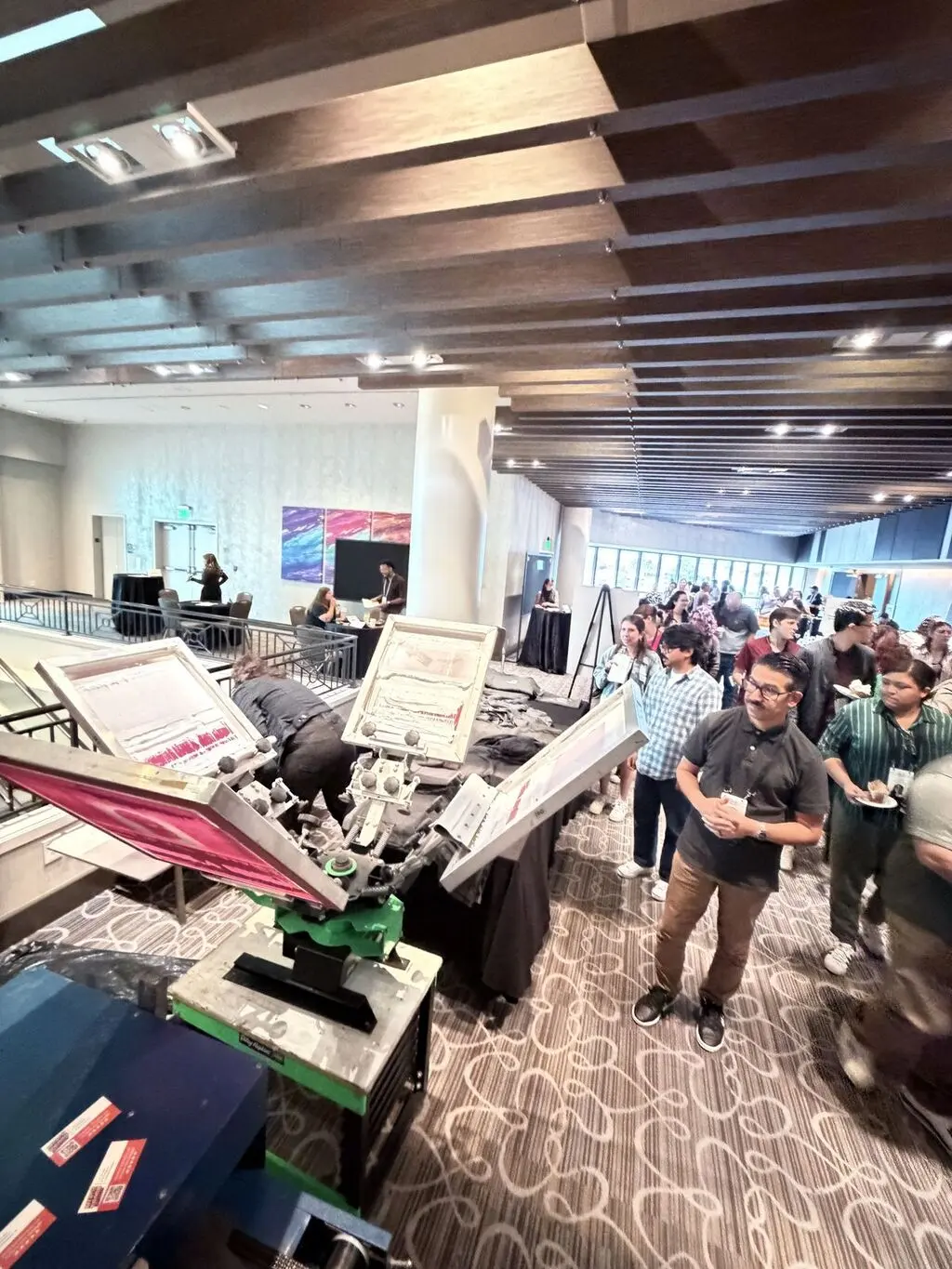 Event guests watching a screen printing press in action